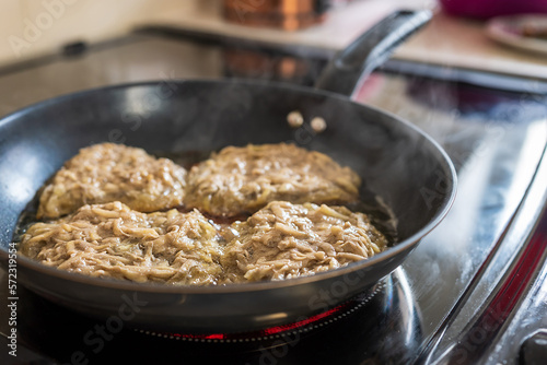 Frying crepe pancake pan with gratet potato on hot cooker hob