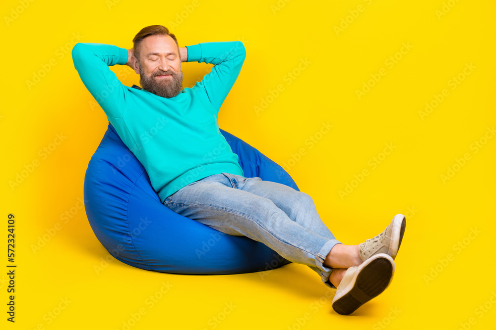 Full size photo of handsome granddad beanbag arms behind head closed eyes dressed stylish cyan garment isolated on yellow color background