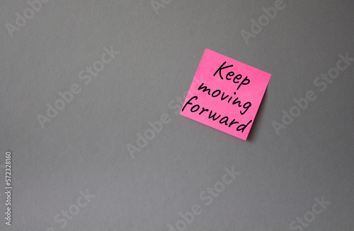 Keep moving forward symbol. Concept words keep moving forward on pink steaky note. Beautiful grey background. Business and keep moving forward concept. Copy space.