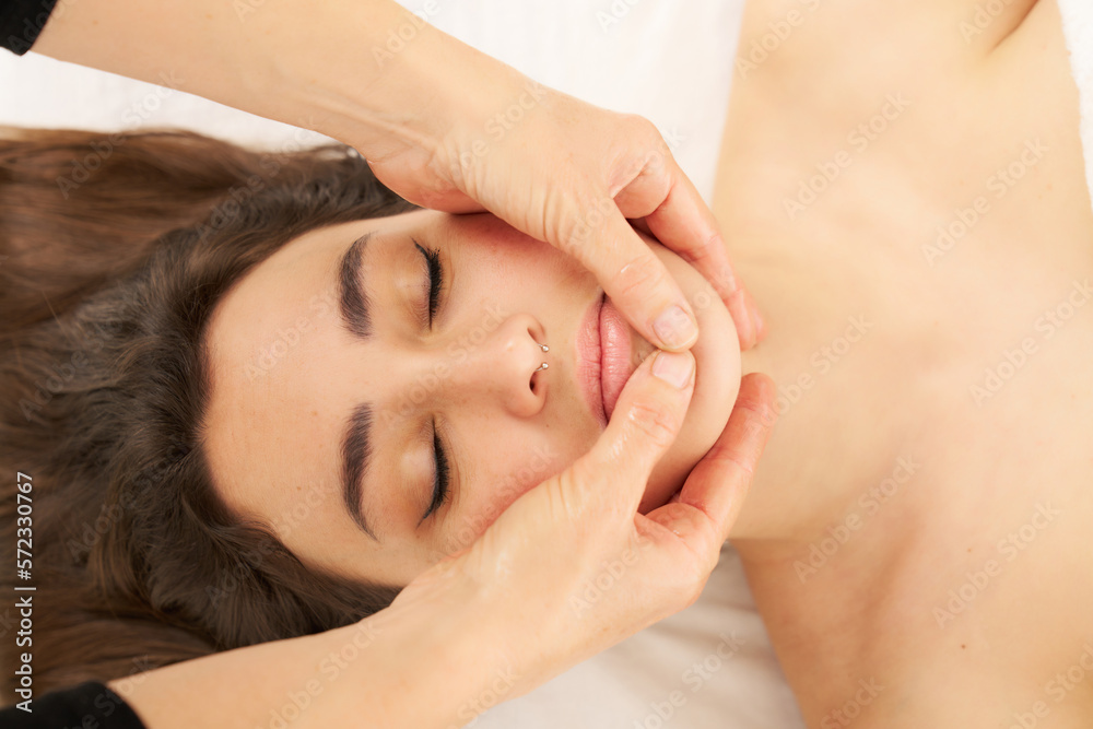therapist massaging a woman's face. Attractive woman receiving facial massage