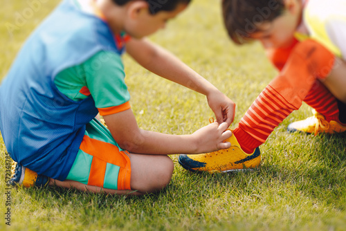 Фотография Young boy helping to friend in tiying shoelaces