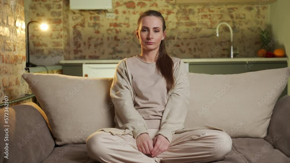 A happy young woman resting at home on the couch looks at the camera and smiles. A happy young woman resting at home on the couch looks at the camera and smiles.