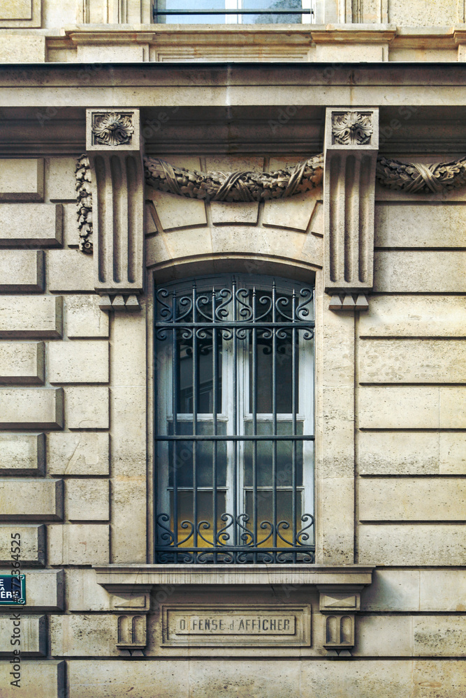 Obraz premium Paris ancient stone building facade with a French window, wrought iron grille and stucco fretwork
