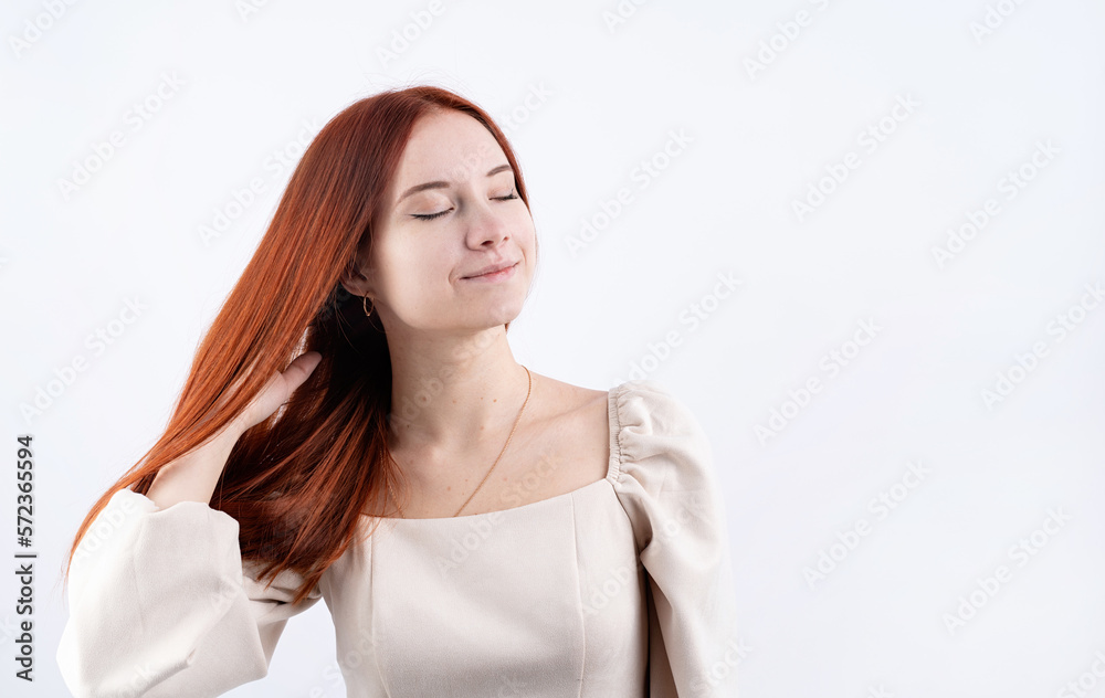 portrait of a young beautiful woman touching her red hair on white background, copy space portrait of a young beautiful woman touching her red hair on white background, copy space