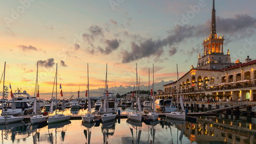 small sailboats in the seaport of Sochi against the backdrop of the maritime station and a beautiful sunset sky