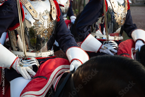 Soldados de caballería de la guardia real montados a caballo con coraza y sable durante un desfile.