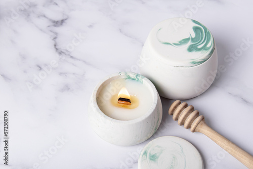 Two candles and wooden honey spoon. Honey-scented candles. Space for text