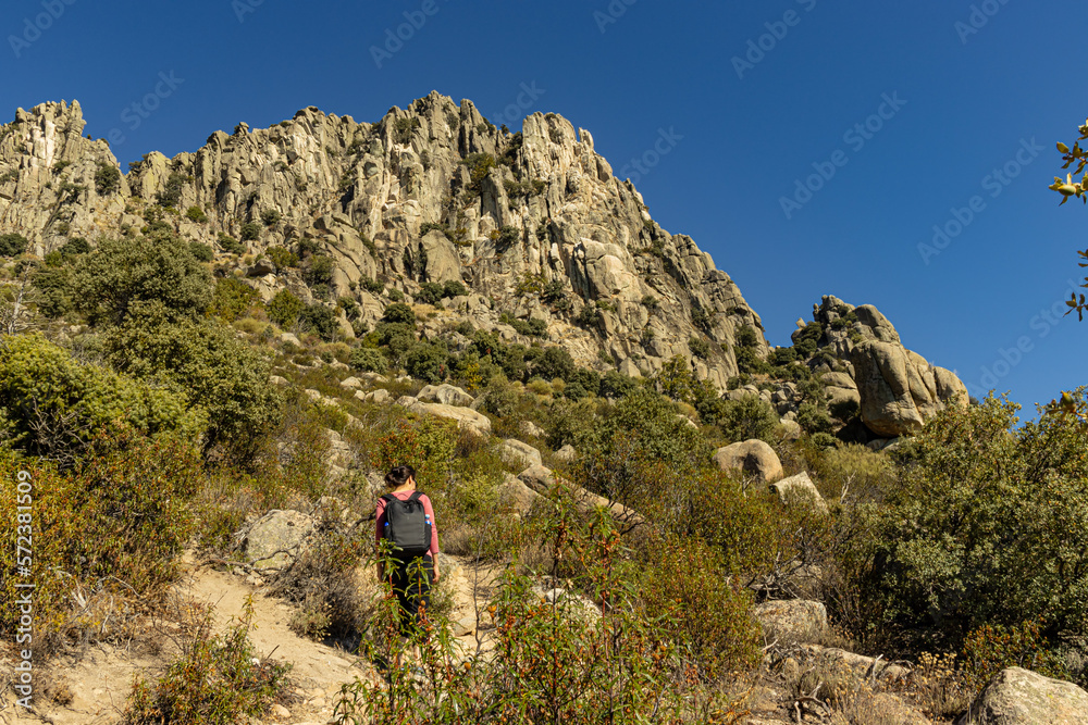 Woman walking at sunset on the Sierra de la Cabrera trail leading to the peak of Cancho Gordo.