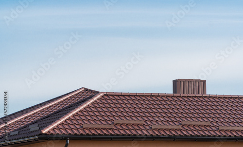 Roof of a house with modern metal roof tiles. Brown metal roof of a modern new house