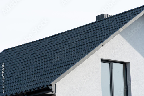 The dark-colored roof of a new residential house. Roof covering with steel tiles