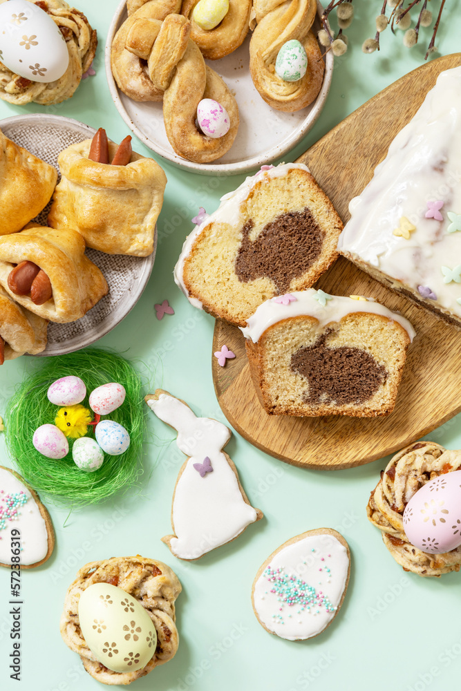 Festive dinner, Easter brunch. Happy Easter holiday food baking puff pastry and cupcake with Easter Bunny on pastel green background. View from above.