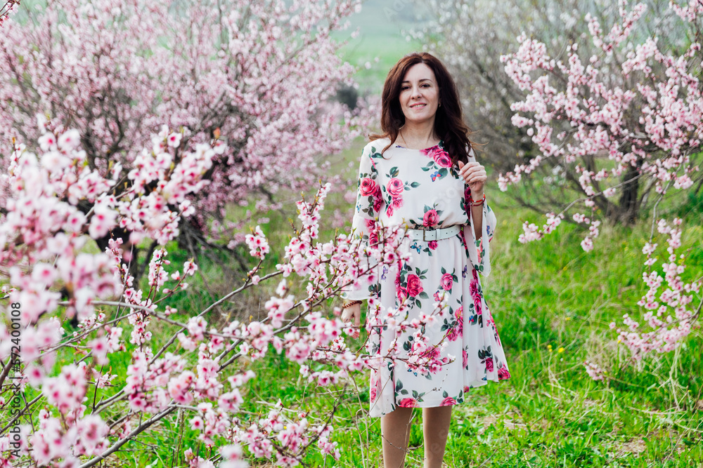 a beautiful woman in flowering trees walks in a park on the street a beautiful woman in flowering trees walks in a park on the street