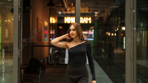 Beautiful happy elegant girl in fashion black clothes with a top and trousers walks in the mall