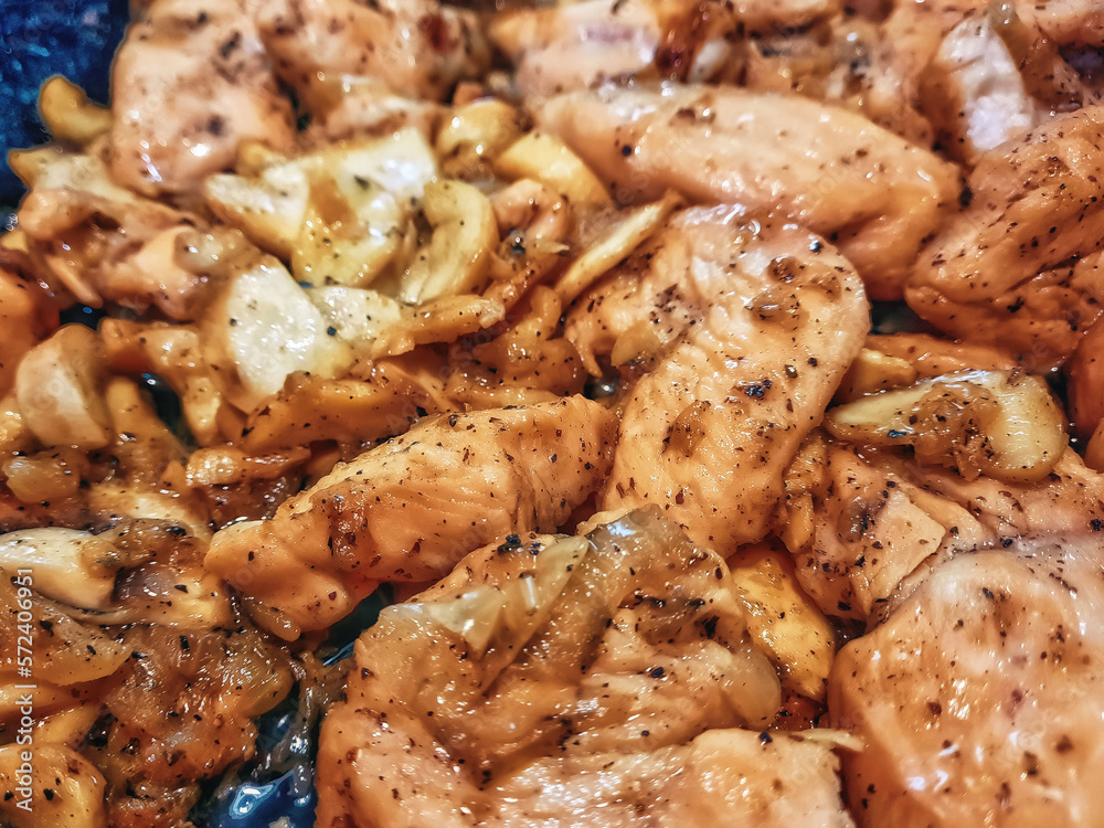 Chicken meat is fried with onions in a skillet