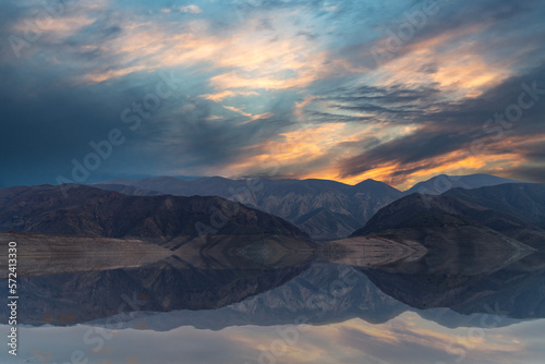 Beautiful sunset over the mountains and lake with reflection in the water. 