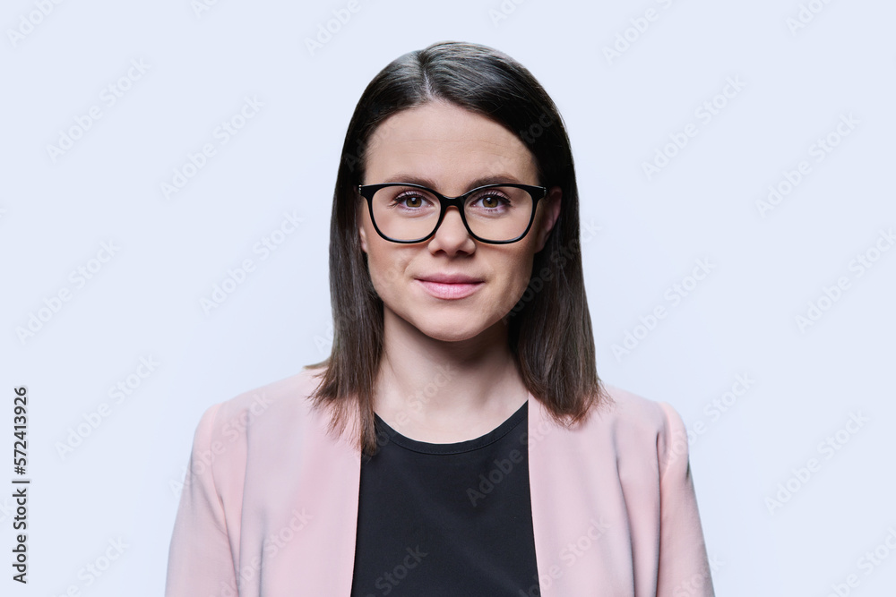 Headshot portrait of young woman in glasses looking at camera on white background Headshot portrait of young woman in glasses looking at camera on white background