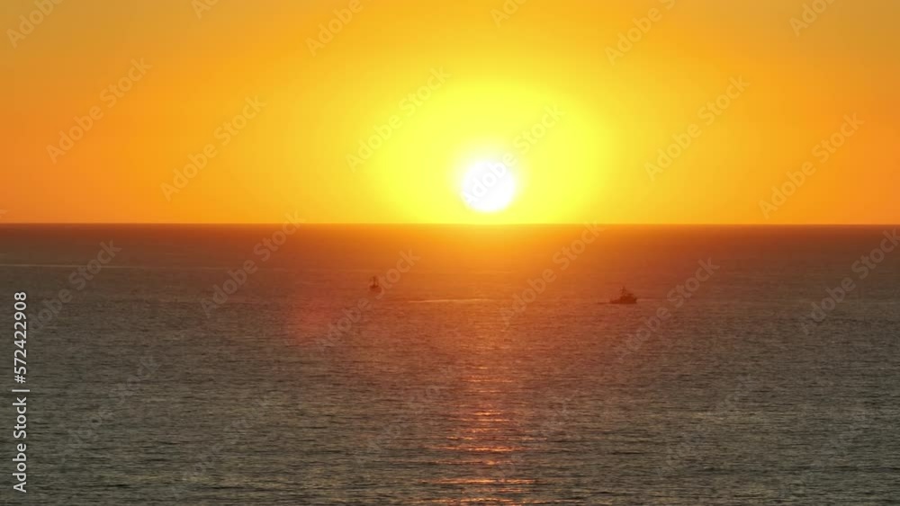 Drone shot of magical golden hour lighting over paradise travel destination. Boat floating across massive, calm sea waters towards the shoreline as bright sun setting behind. High quality 4k footage Drone shot of magical golden hour lighting over paradise travel destination. Boat floating across massive, calm sea waters towards the shoreline as bright sun setting behind. High quality 4k footage