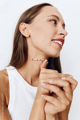 Portrait of a young beautiful woman with tanned skin model on a white background in a white T-shirt with a chain around her neck