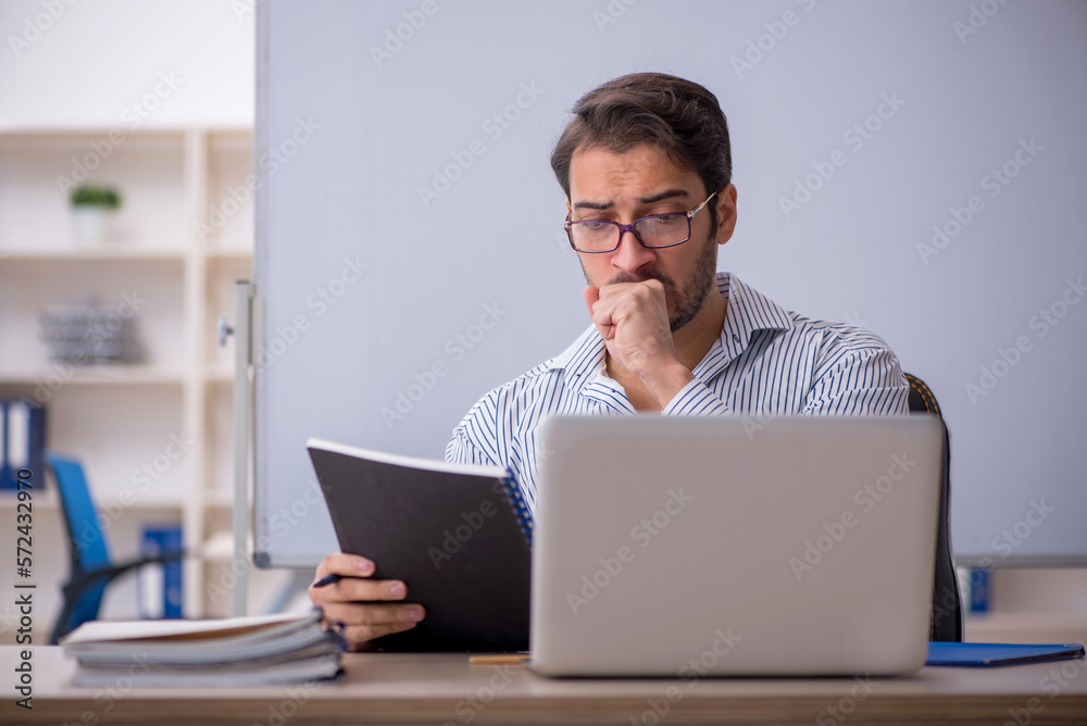 Young male teacher sitting in the classroom Young male teacher sitting in the classroom