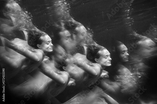 Young beautifull caucasian woman in dress under water in black and white
