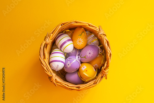 easter eggs in a basket on a yellow background, top view