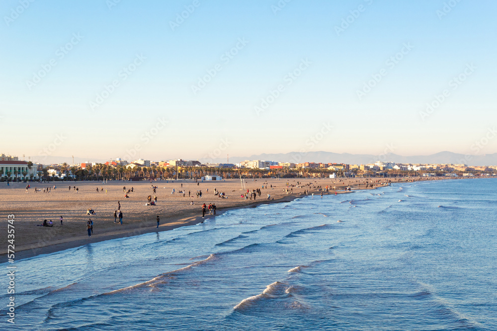 People walking along the shore of Malvarrosa beach on a quiet Sunday afternoon. Valencia - Spain