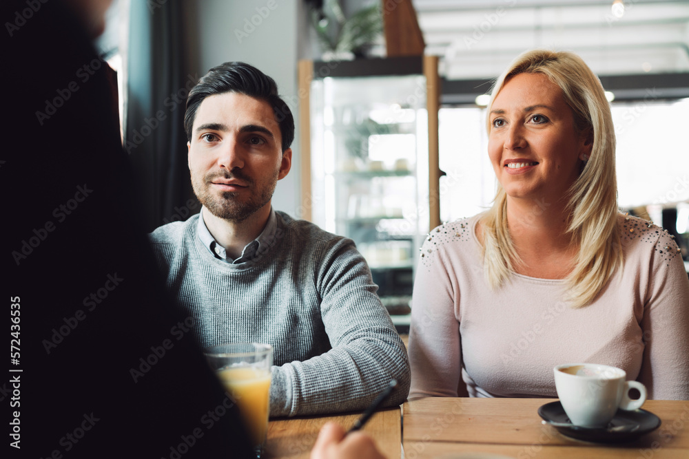 Smiling caucasian couple sitting at the desk across from their financial advisor, carefully listening to what he is saying Smiling caucasian couple sitting at the desk across from their financial advisor, carefully listening to what he is saying