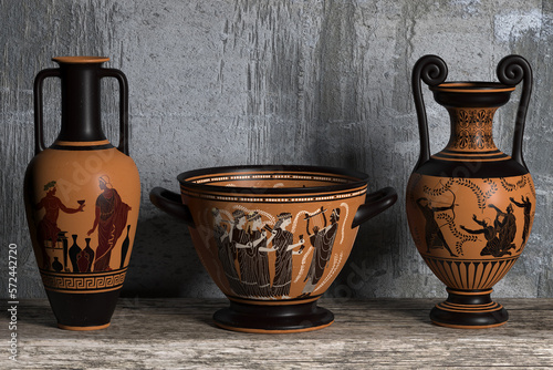 Three ancient Greek wine vases of different shapes with meander ornaments and various patterns stand in a row on a wooden shelf against a concrete wall. 3d render.