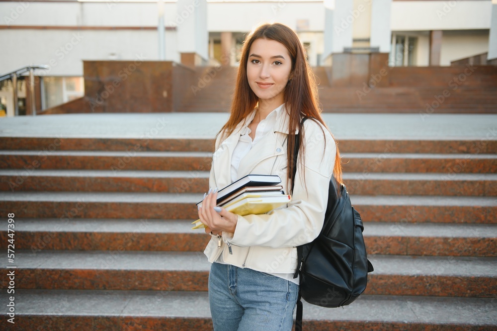 Cheerful attractive young woman with backpack and notebooks standing and smiling. Cheerful attractive young woman with backpack and notebooks standing and smiling.