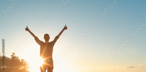 Young woman with thumbs up feeling positive and joyful free in nature sunset