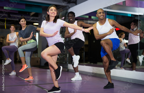 Cheerful young adult men and women training in dance studio, dance class for adults © JackF