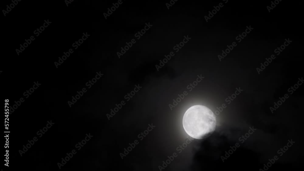 Black clouds float smoothly across the full moon at night. Dramatic Halloween concept in nature. Black clouds float smoothly across the full moon at night. Dramatic Halloween concept in nature.