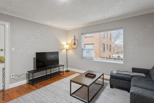 White apartment with wide open spaces  hardwood flooring and modern furniture. Used as a short term rental. 