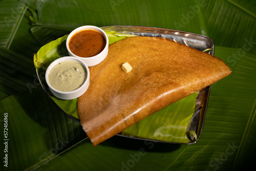 A masala dosa served with sauces and topped with a cube of butter.