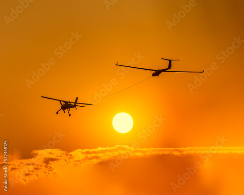 Glider towed by ultralight aircraft at sunset