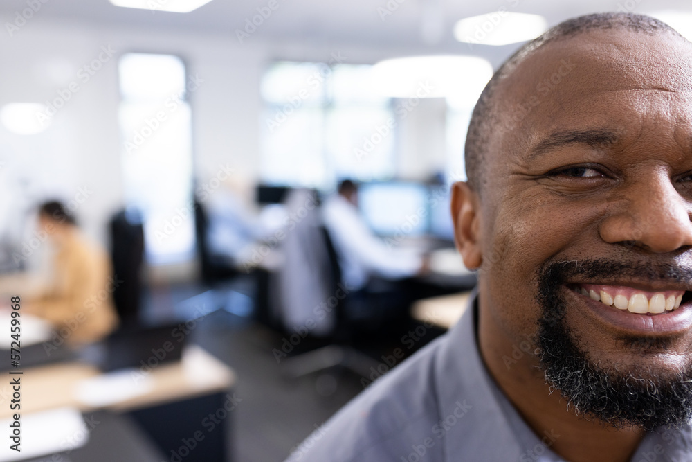 Happy african american businessman looking at camera in office