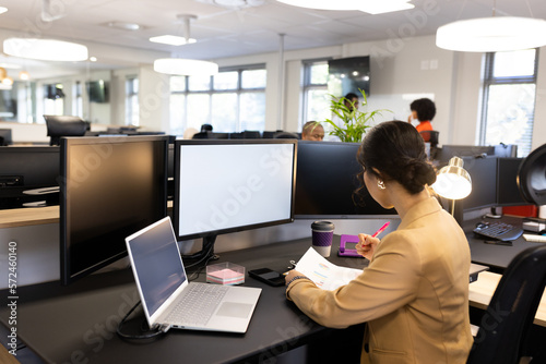 Asian woman sitting at desk and working on computer with copy space in office