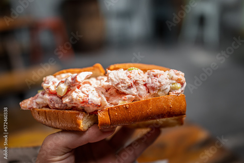 Maine lobster roll sandwich in brioche bun bread in seafood restaurant cafe in Key West, Florida with hand holding macro closeup photo