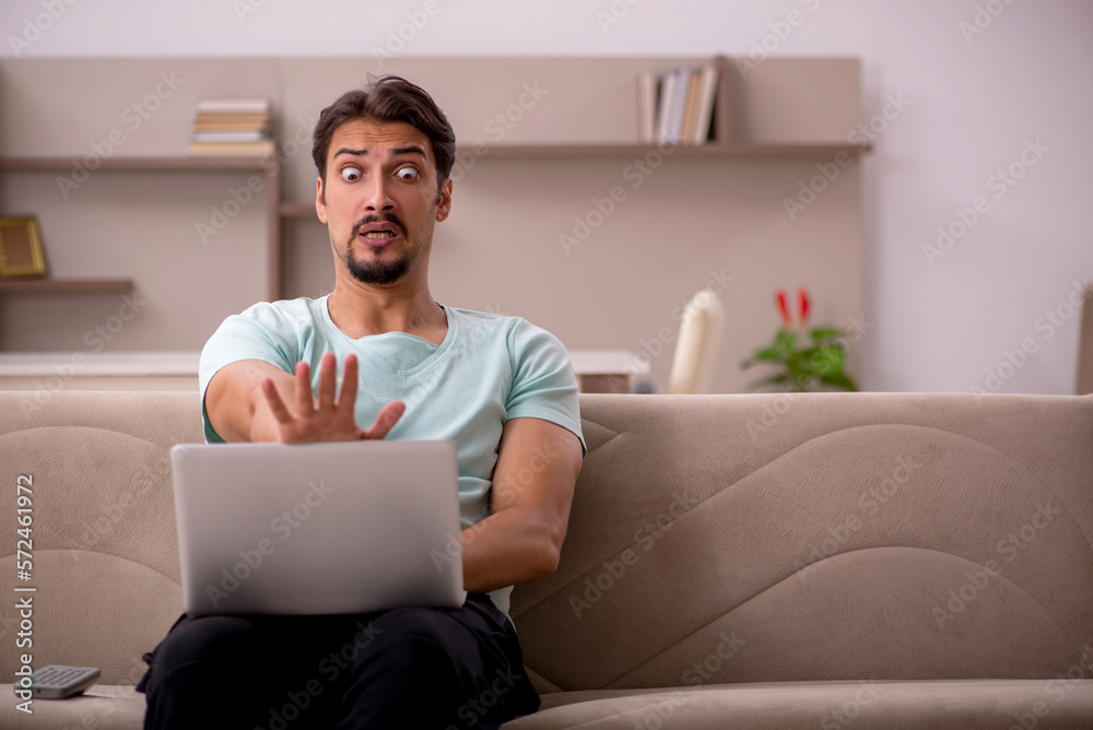 Young man sitting on the sofa with computer at home