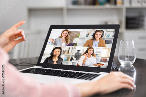 Woman talking with female co-workers via video call at home.