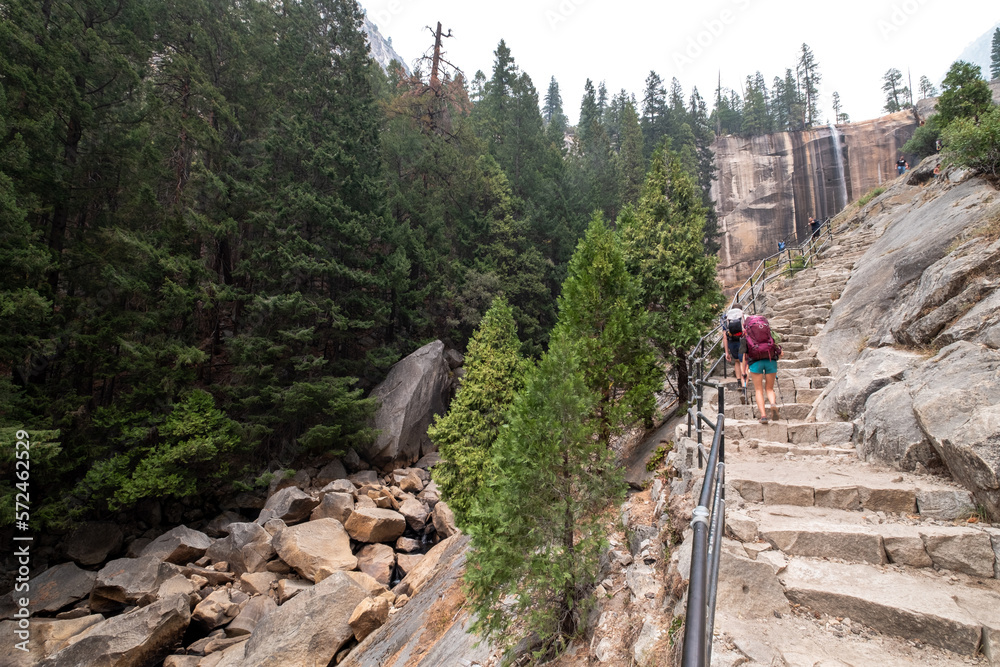 Trail and stairs that ascend to the base of Vernal Falls, with a couple of tourists with backpacks going up .Yosemite NP