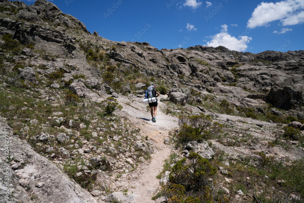 View of a woman hiking along the path in the rock massif Los Gigantes in Cordoba, Argentina. View of the rocky hills in a sunny day.