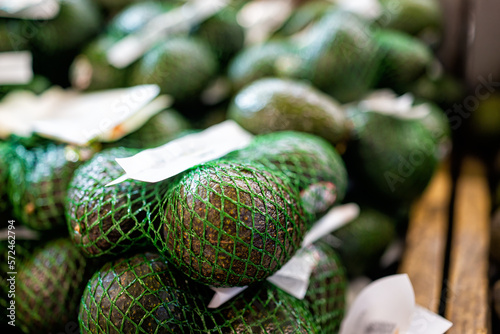 Avocados on grocery produce store shop supermarket display, raw unripe tropical green fruit in mesh net bags