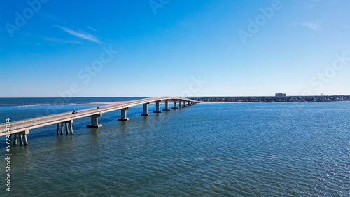 Aerial drone view of a smooth long bridge over a dark blue body of water