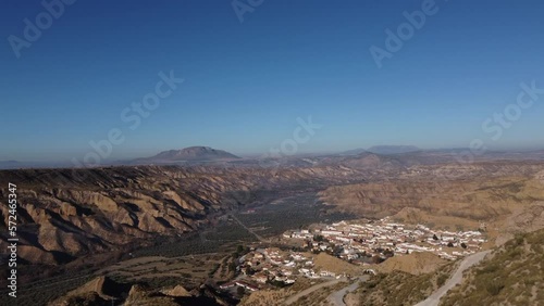 Aerial Drone view of dry valley and mountains at Gorafe, Desierto de los Coloraos in Blue sky, Sierra Nevada, Granada, Spain. Spanish desert canyon with vegetation, in Andalusia. Flying over mountain