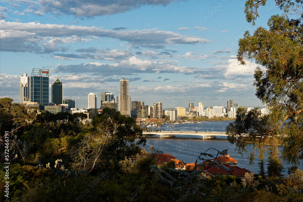 Fototapeta premium View to the centre of Perth in Western Australia, landscape with the skyscrapers, parks and bay with the bridge during sunset or sunrise. Clouds on the dramatic blue sky