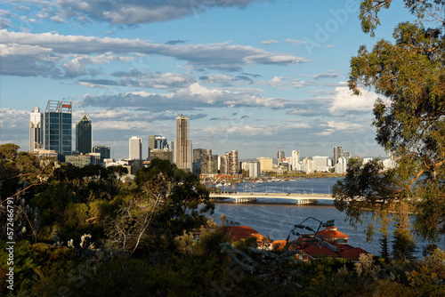 View to the centre of Perth in Western Australia, landscape with the skyscrapers, parks and bay with the bridge during sunset or sunrise. Clouds on the dramatic blue sky