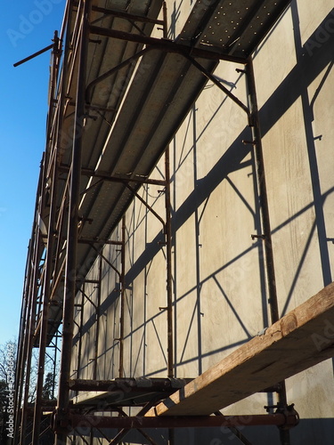 Scaffolding on a new one-story house. Facade works. Building bussiness. Low-rise private building. Plastering the wall of a building. Shop building. Metal production structures.