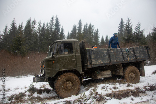 An old military truck in the swamp of green color with big dirty wheels in the forest