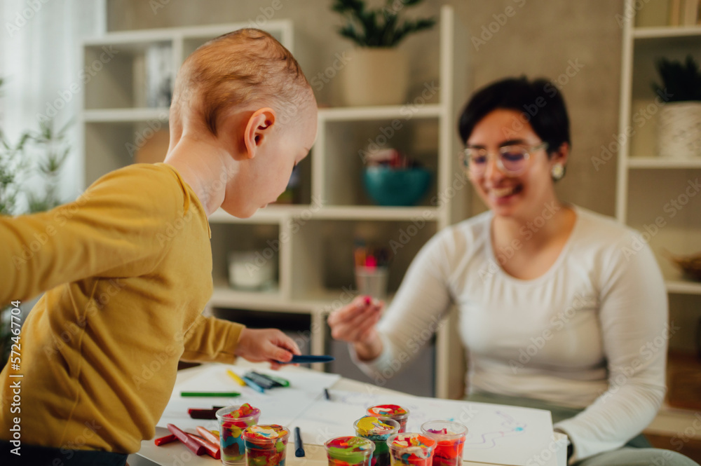 Mother and son drawing with crayons at home and having education